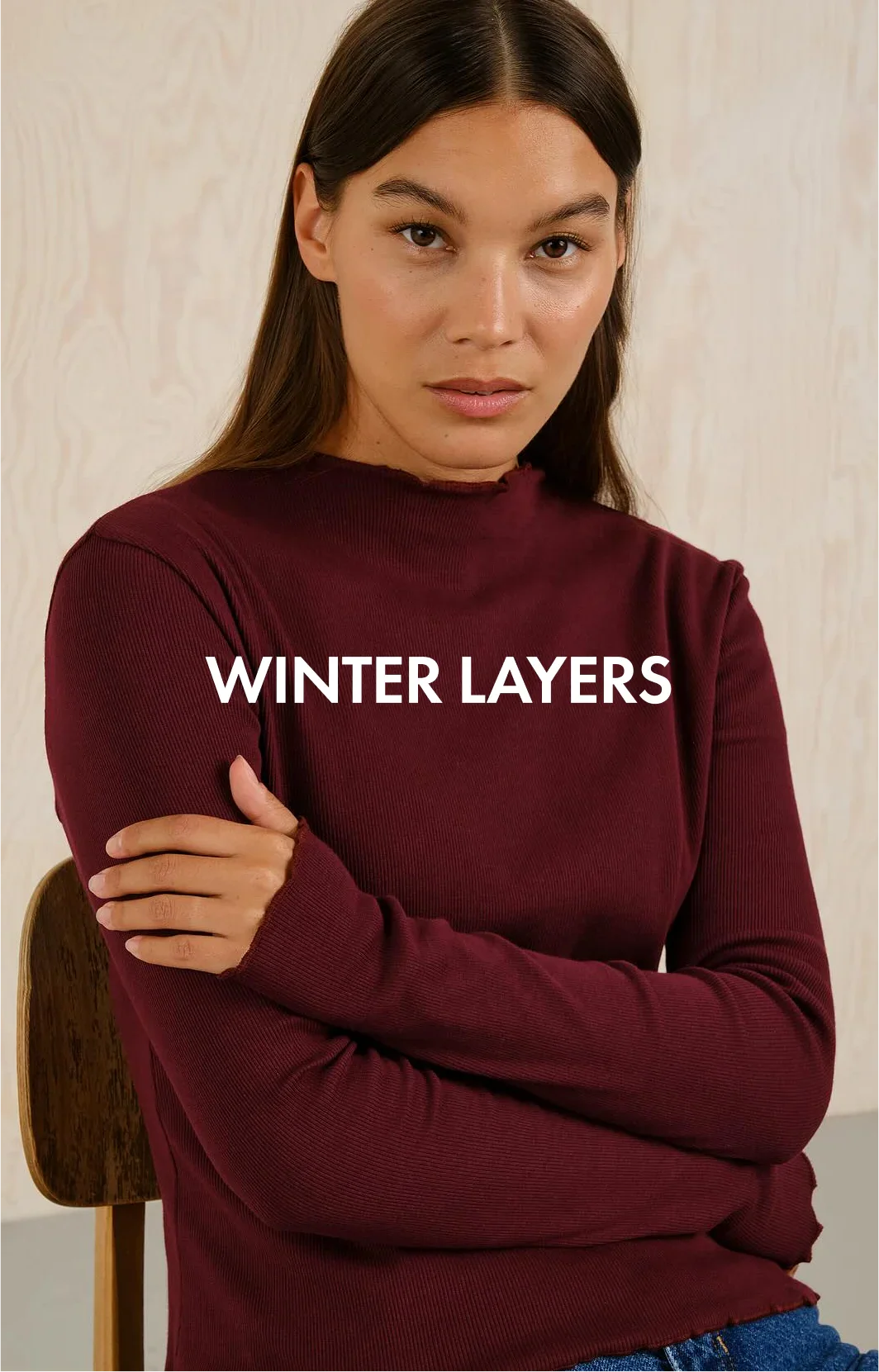 Woman in a burgundy ribbed long-sleeve top with folded arms, winter layers fashion
