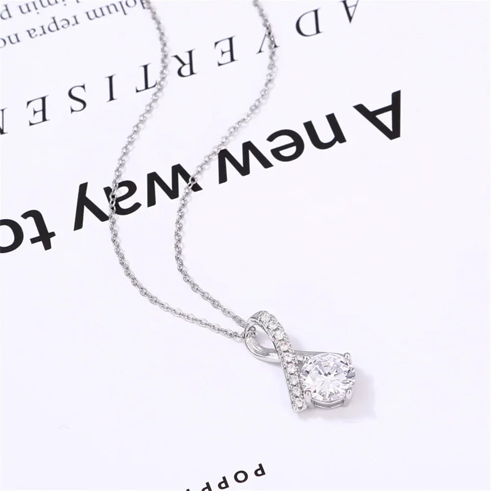 Silver pendant necklace with a twisted design and sparkling round crystal on white background