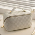 Elegant white checkered makeup bag with gold zipper and handle on vanity table